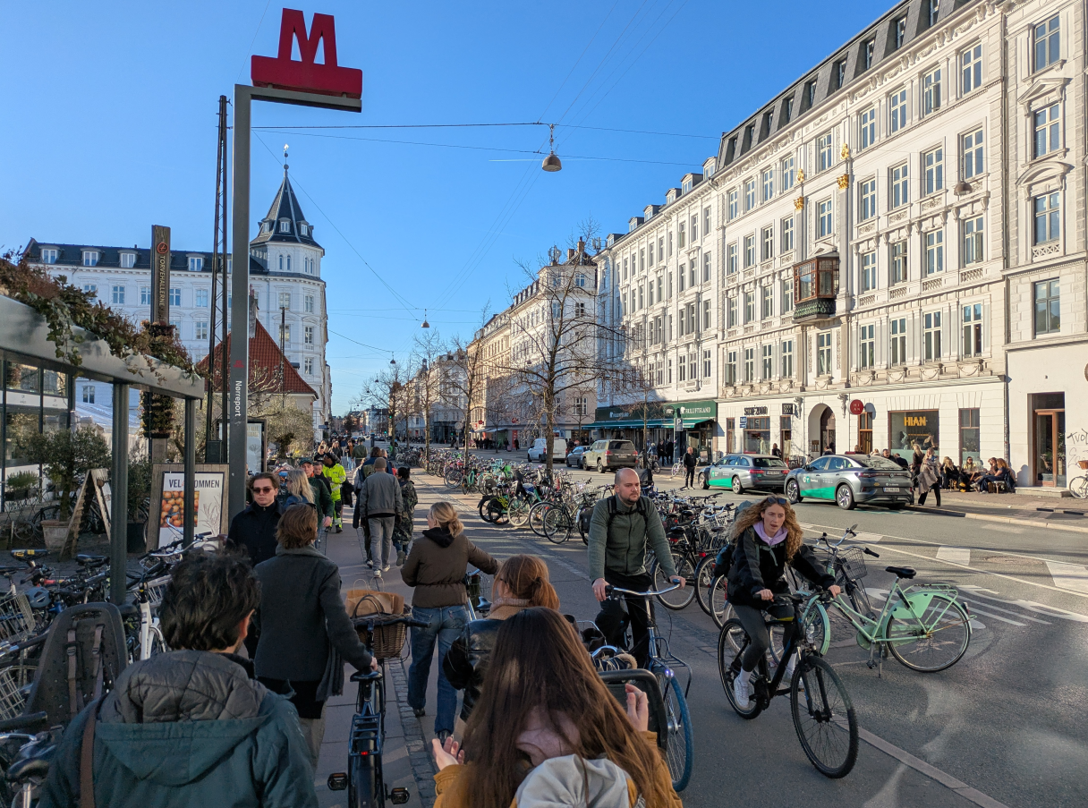 Central Copenhagen, highlighting the high throughflow of pedestrians and cyclists enabled by space allocation policies, and the fact that there are bike parking spaces *everywhere* in the city.
